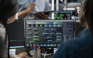 Close up of data center programmers using PC to visualize artificial intelligence neural networks. Server farm IT experts looking at monitor, working together to oversee AI systems